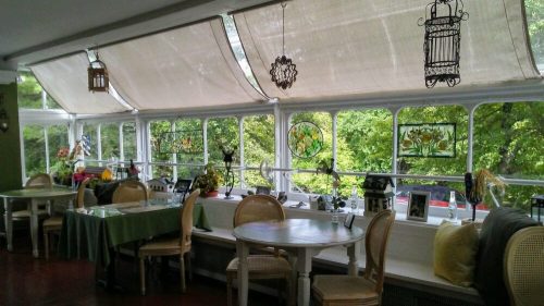 Bright, airy restaurant interior with large windows, stained glass decorations, and tables set for dining.