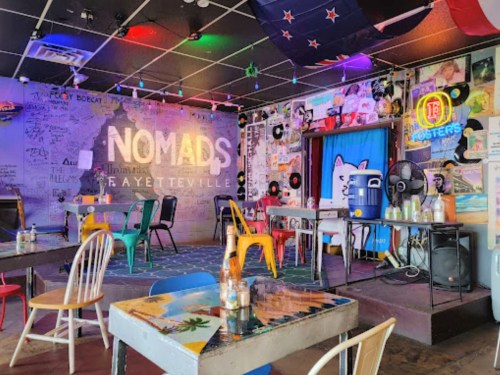 Colorful interior of Nomads restaurant in Fayetteville, featuring eclectic decor, tables, and vibrant seating.