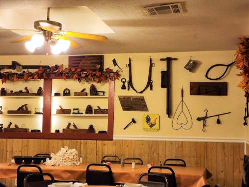 A cozy dining area with rustic decor, featuring vintage tools and autumn-themed decorations on the walls.