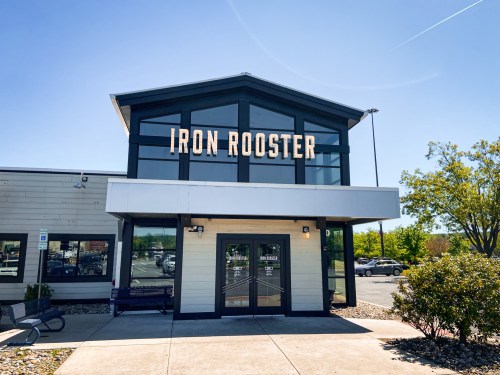 Exterior of the Iron Rooster restaurant, featuring a modern design and clear blue sky.