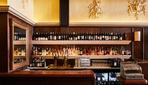 A stylish bar with wooden shelves lined with various bottles of wine and spirits, and a polished countertop.
