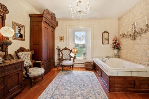 Elegant vintage bathroom featuring a freestanding tub, antique furniture, and decorative wall art.