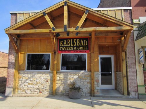 Exterior of Karlsbad Tavern & Grill featuring a wooden structure, stone accents, and a sign with the restaurant's name.