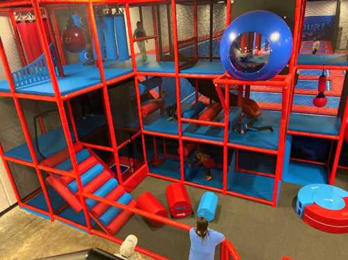 A colorful indoor play structure with slides, tunnels, and climbing areas, filled with children playing and exploring.