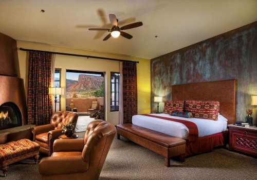 Cozy hotel room with a king bed, seating area, fireplace, and large window showcasing a scenic view.
