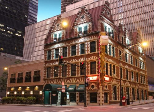 Historic building with ornate architecture, featuring bright lights and a marquee, set in an urban cityscape.