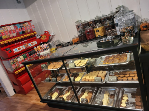 A display case filled with various baked goods and jars of colorful candies in a sweet shop.