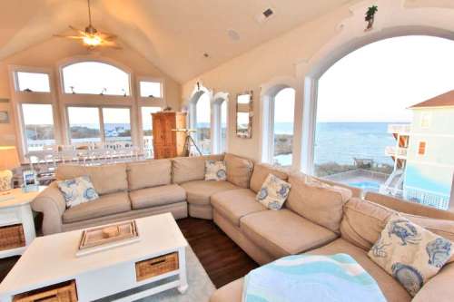 Cozy living room with a large sectional sofa, ocean views, and bright windows, creating a welcoming atmosphere.