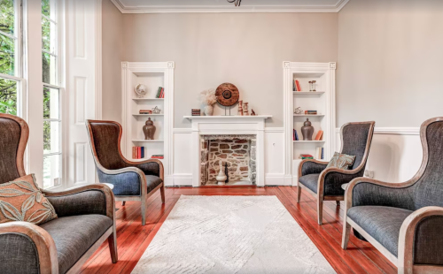 Cozy living room with two armchairs, a fireplace, and built-in shelves displaying decorative items and books.