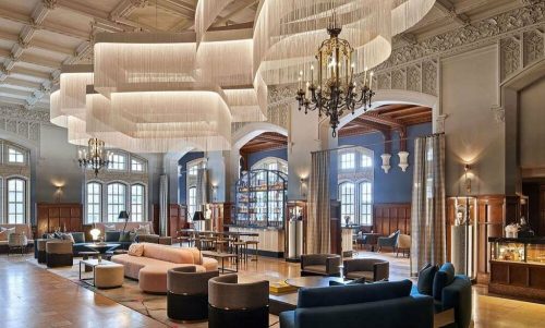 Elegant hotel lobby featuring modern furnishings, large chandeliers, and intricate architectural details.