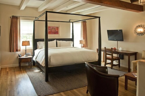 Cozy bedroom featuring a four-poster bed, wooden furniture, and warm lighting.