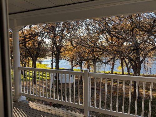 View from a porch overlooking a river surrounded by trees with autumn foliage.