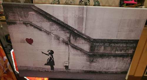 A girl with a balloon stands on stairs, with the text "There is always hope" on the wall beside her.