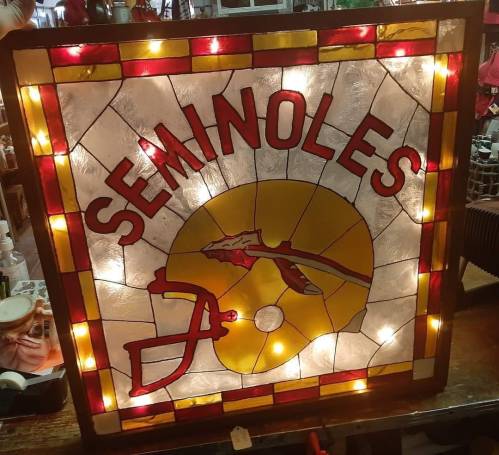 Stained glass sign featuring "SEMINOLES" with a yellow background and a red football helmet design.