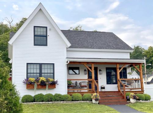 A charming white house with a porch, flower boxes, and a well-maintained lawn under a partly cloudy sky.