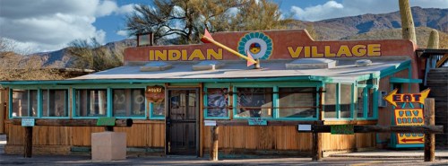Colorful building with "Indian Village" sign, featuring a rustic wooden exterior and vibrant decorations.