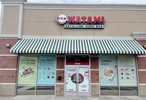 Exterior of Watami Revolving Sushi Bar, featuring a striped awning and promotional signage on the windows.