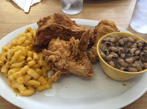A plate of fried chicken with macaroni and cheese and black-eyed peas on the side.