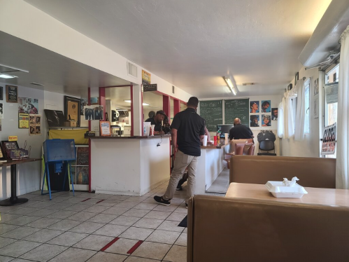 Interior of a casual diner with a counter, tables, and staff serving customers. Brightly lit with a welcoming atmosphere.