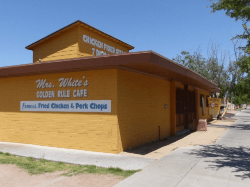 A yellow building with a sign for Mrs. White's Golden Rule Cafe, advertising fried chicken and pork chops.