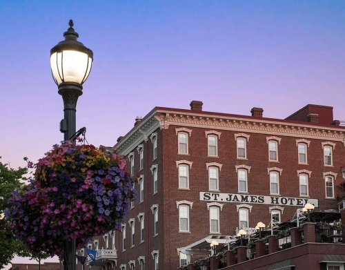 Historic St. James Hotel at dusk, with a lamppost and vibrant flower basket in the foreground.