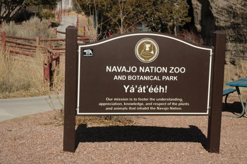 Sign for Navajo Nation Zoo and Botanical Park, stating its mission to promote understanding and respect for local flora and fauna.