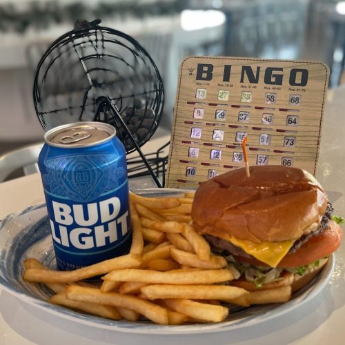 A plate with a cheeseburger, fries, a can of Bud Light, and a bingo card in the background.
