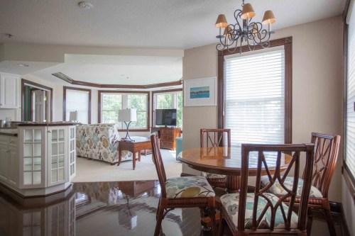 Bright, modern dining area with a round table, chairs, and a view of a cozy living space with large windows.