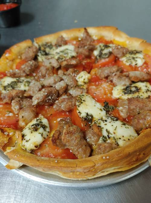 A freshly baked pizza topped with sausage, mozzarella, and herbs on a golden crust.