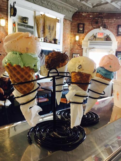 A display of colorful ice cream cones in a shop, featuring flavors like mint, chocolate, and strawberry.