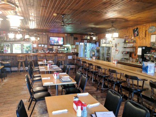 Cozy diner interior with wooden decor, empty tables, a bar area, and warm lighting.