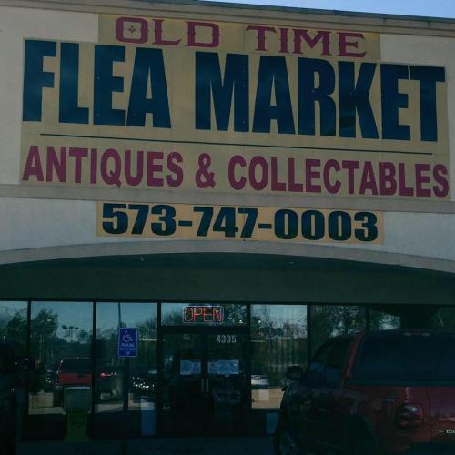 Sign for "Old Time Flea Market" featuring antiques and collectibles, with a visible phone number and "Open" sign.