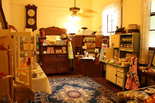 A cozy vintage shop interior with wooden furniture, shelves of jars, and a colorful rug, creating a warm atmosphere.