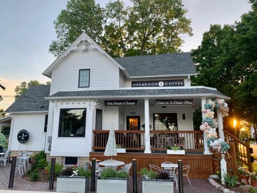 A charming white house converted into a coffee shop, featuring a porch and colorful balloon decorations.