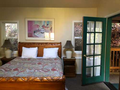 Cozy bedroom with a wooden bed, colorful bedding, lamps, and a green door leading to an outdoor area.