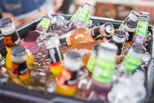 A cooler filled with various colorful bottled drinks surrounded by ice.