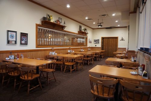 Interior of a cozy restaurant with wooden tables and chairs, featuring a warm, inviting atmosphere.