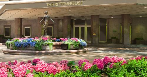 A statue surrounded by colorful flowers at the entrance of The Rittenhouse hotel.