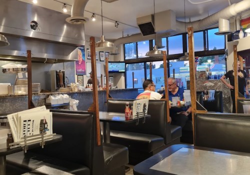 A cozy diner interior with black booths, metal fixtures, and patrons enjoying their meals in a warm atmosphere.