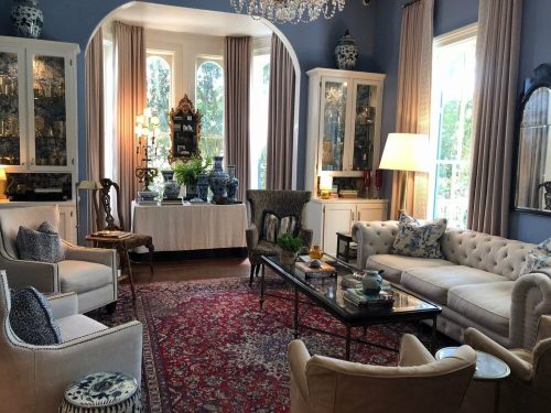 A stylish living room featuring a mix of elegant furniture, decorative blue accents, and a vibrant area rug.