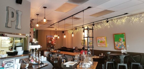 Cozy café interior with warm lighting, wooden counter, and colorful artwork on the walls.