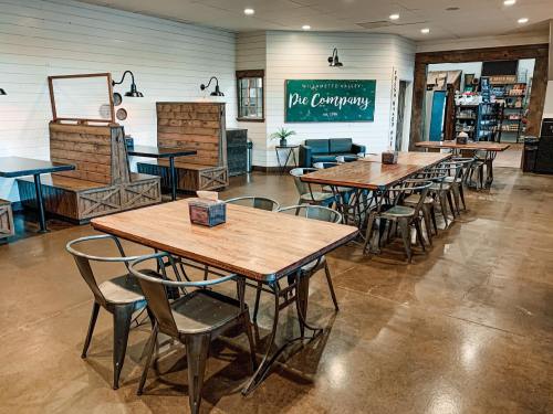 A cozy interior of a pie company with wooden tables, metal chairs, and a welcoming sign on the wall.