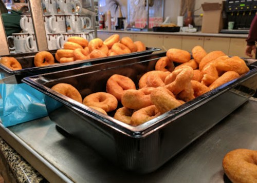 A large tray filled with freshly made donuts, golden brown and piled high.