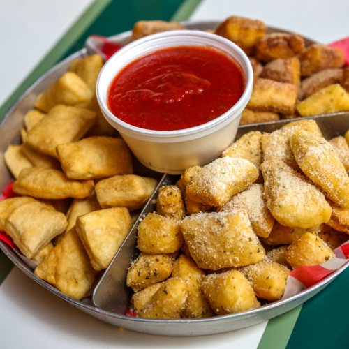 A metal tray filled with various fried snacks and a cup of marinara sauce in the center.