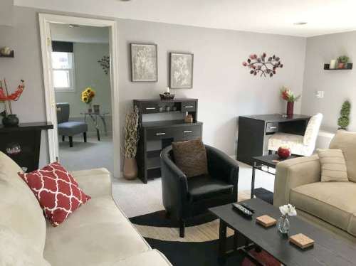 Cozy living room with neutral tones, modern furniture, and decorative plants, featuring a sofa and a desk area.
