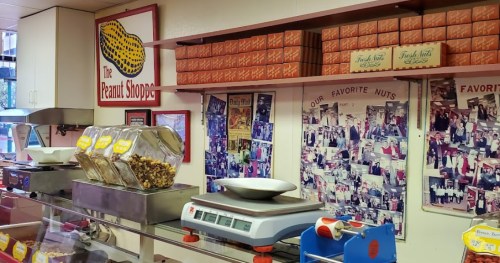 Interior of The Peanut Shoppe, featuring jars of nuts, a scale, and a wall of photos showcasing the shop's history.