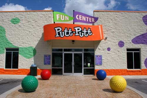 Colorful entrance of a Putt-Putt Fun Center with large, decorative golf balls in front and vibrant wall designs.