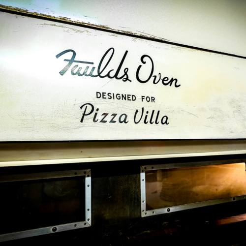 Sign on an oven reading "Faulds Oven Designed for Pizza Villa" with a vintage design.
