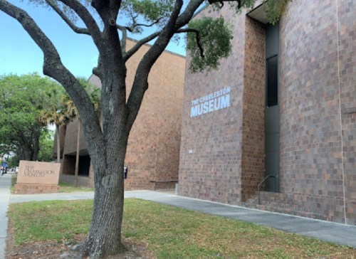 Exterior view of the Charleston Museum, featuring a brick facade and a nearby tree.