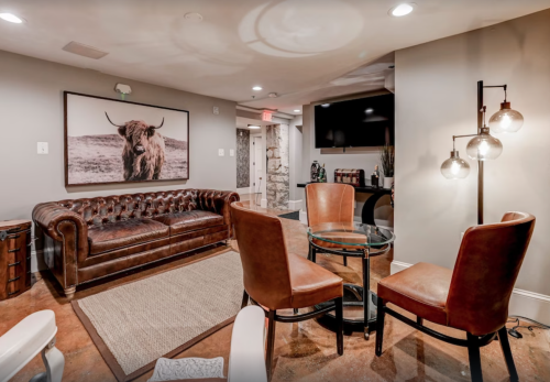 Cozy lounge area featuring a leather sofa, glass table, and stylish chairs, with a large bull portrait on the wall.